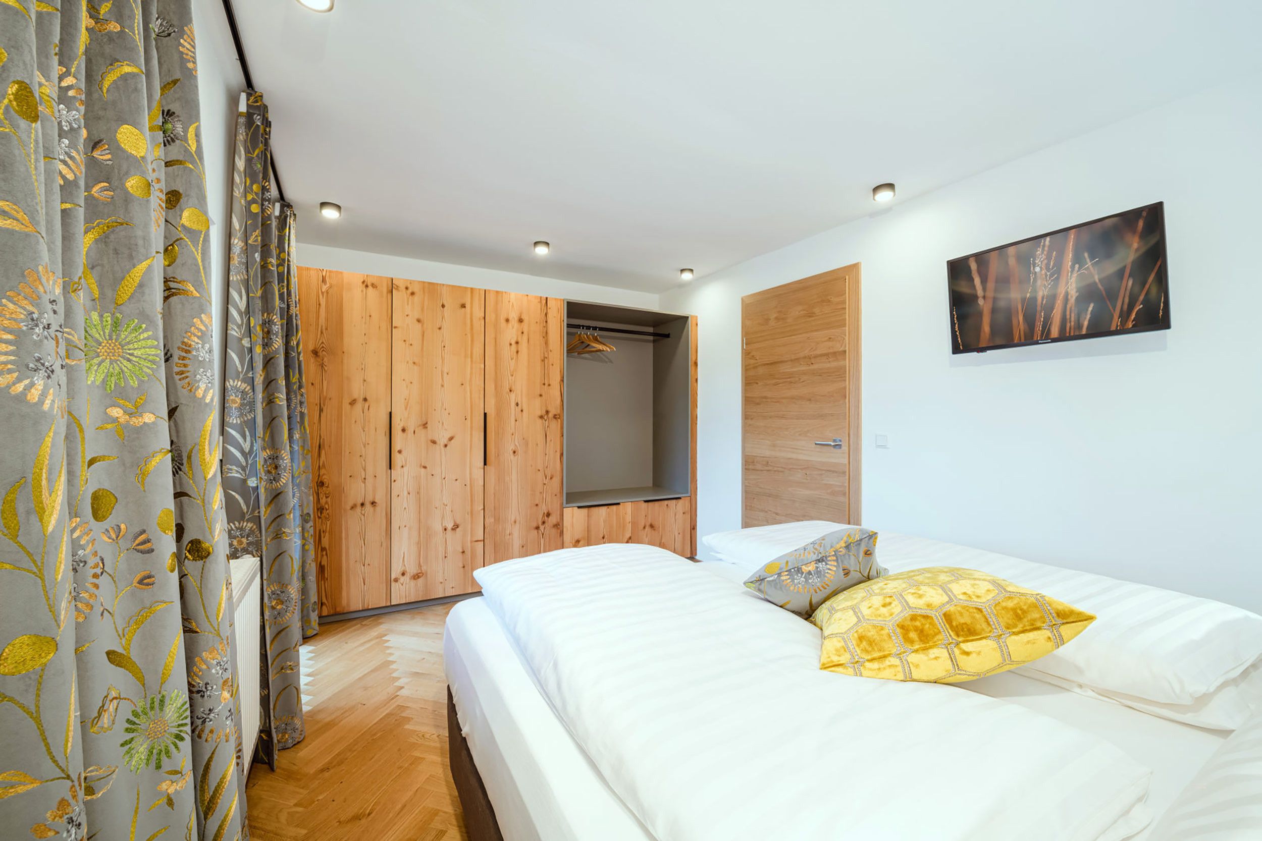Una camera da letto con un letto, un armadio in legno, uno specchio e un quadro appeso al muro.