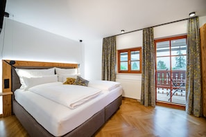 Ein Schlafzimmer mit einem hölzernen Bett, einem Fenster mit Vorhängen und Blick ins Freie.