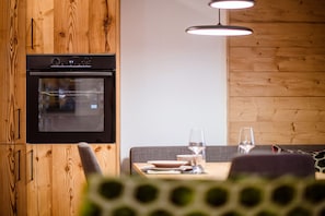 Una cucina moderna con forno integrato, mobili in legno e zona pranzo con tavolo e sedie.