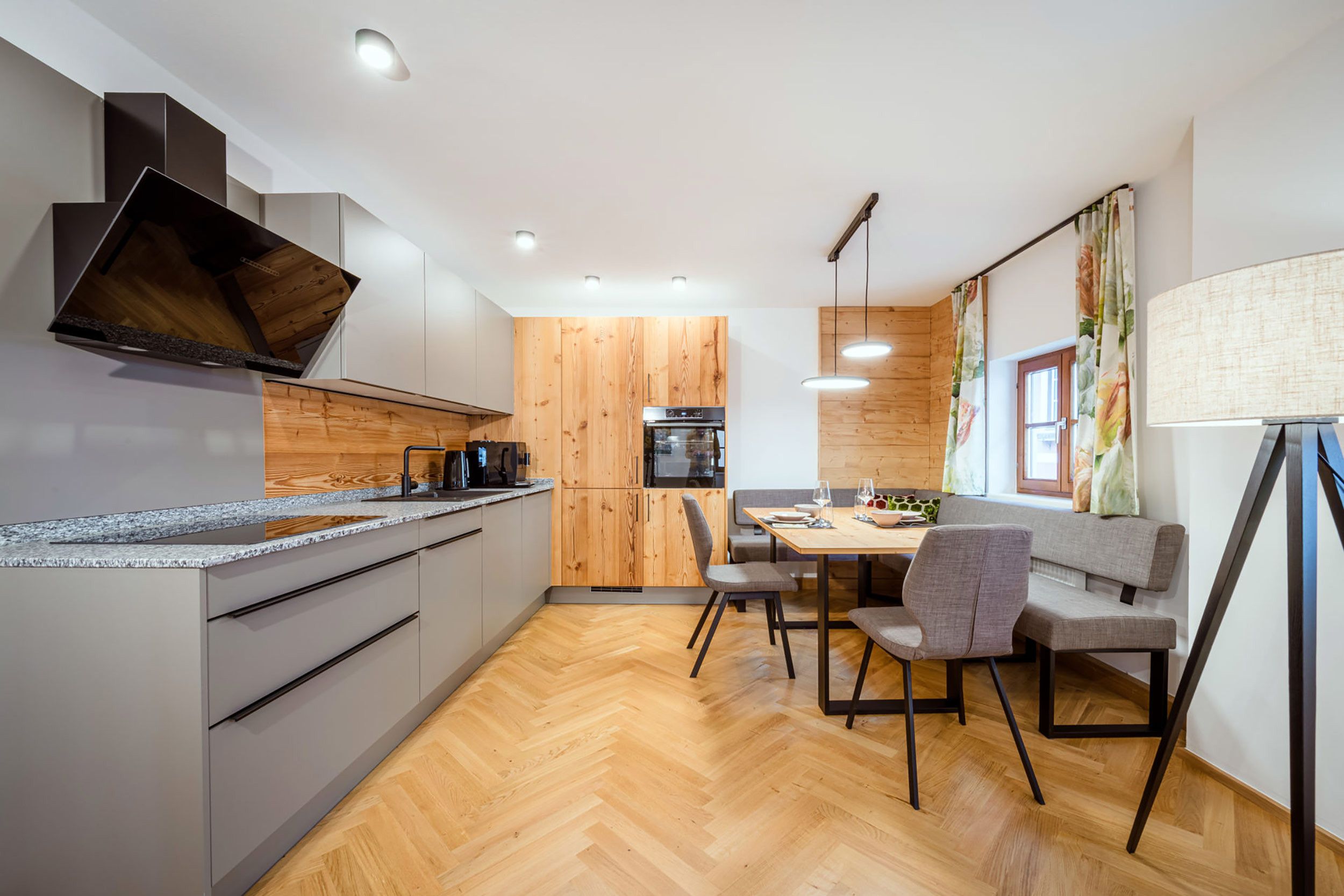Eine moderne Küche mit Backofen, ein Essbereich mit Tisch und Stühlen sowie Holzboden.