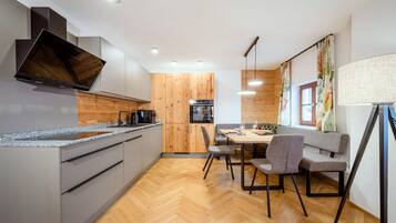 Eine moderne Küche mit Backofen, ein Essbereich mit Tisch und Stühlen sowie Holzboden.