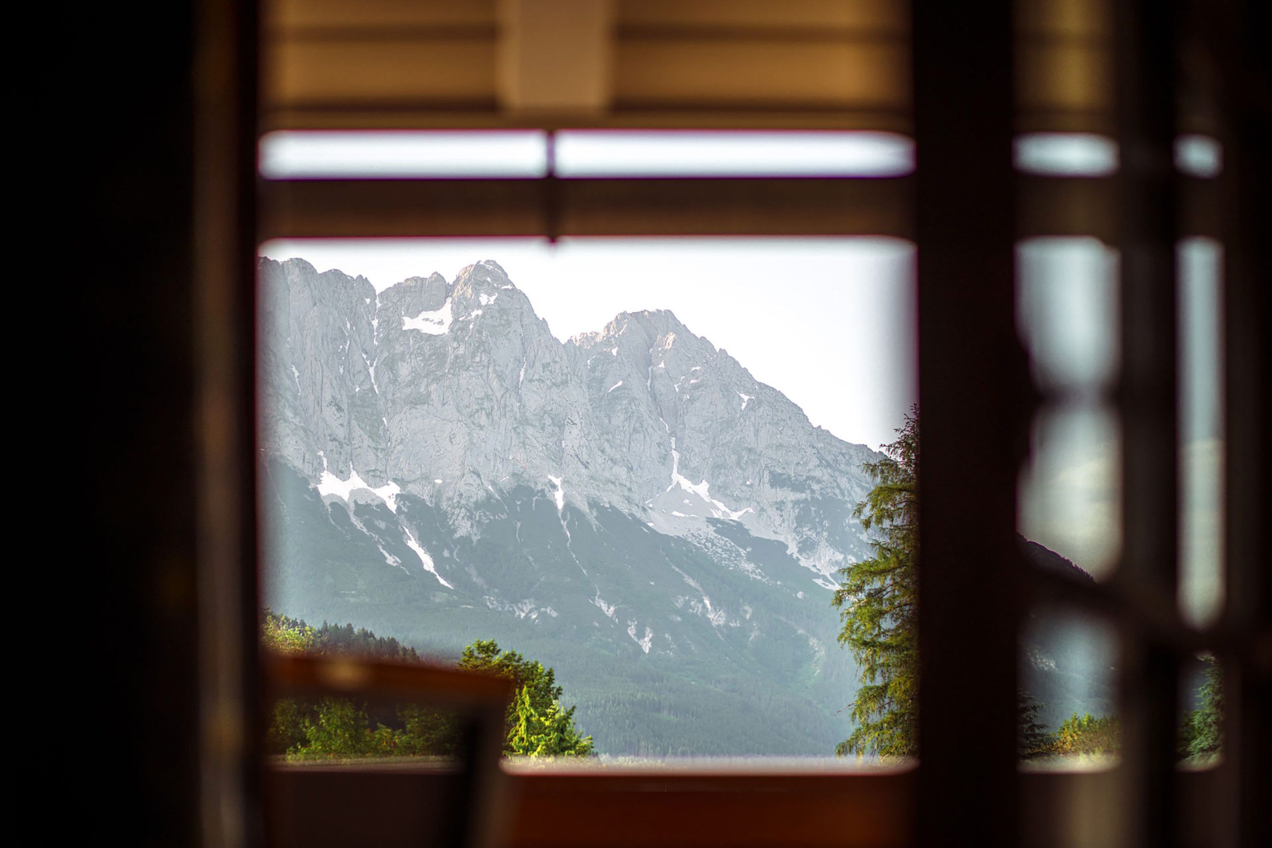 Paesaggio montano visibile da una finestra con cornice in legno.
