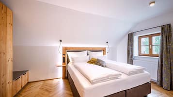 A bedroom with a wooden headboard, a bed with white bedding, a window with curtains, and a radiator.