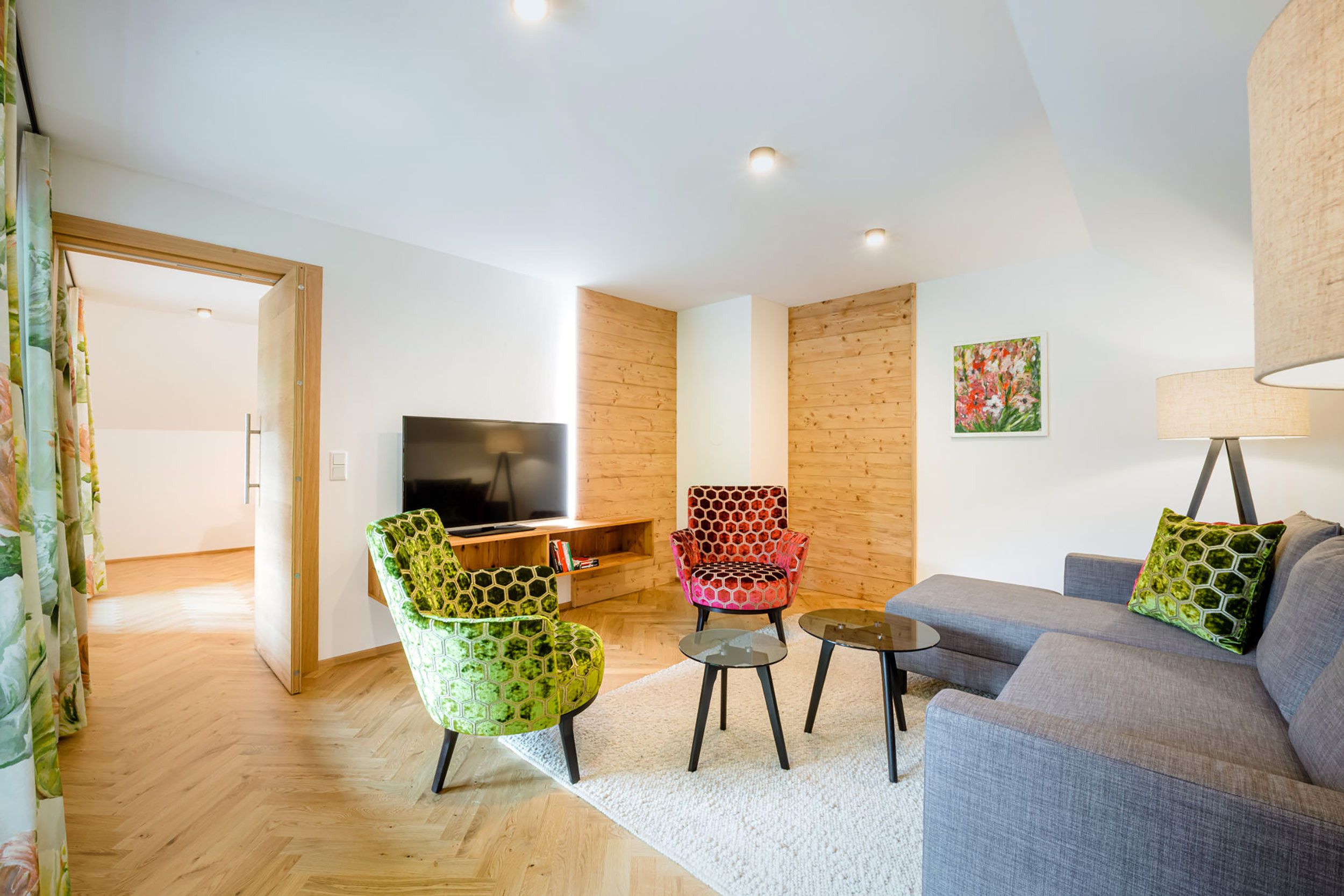 A modern living room with a sofa, two chairs, a coffee table, and a television.
