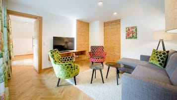 A modern living room with a sofa, two chairs, a coffee table, and a television.