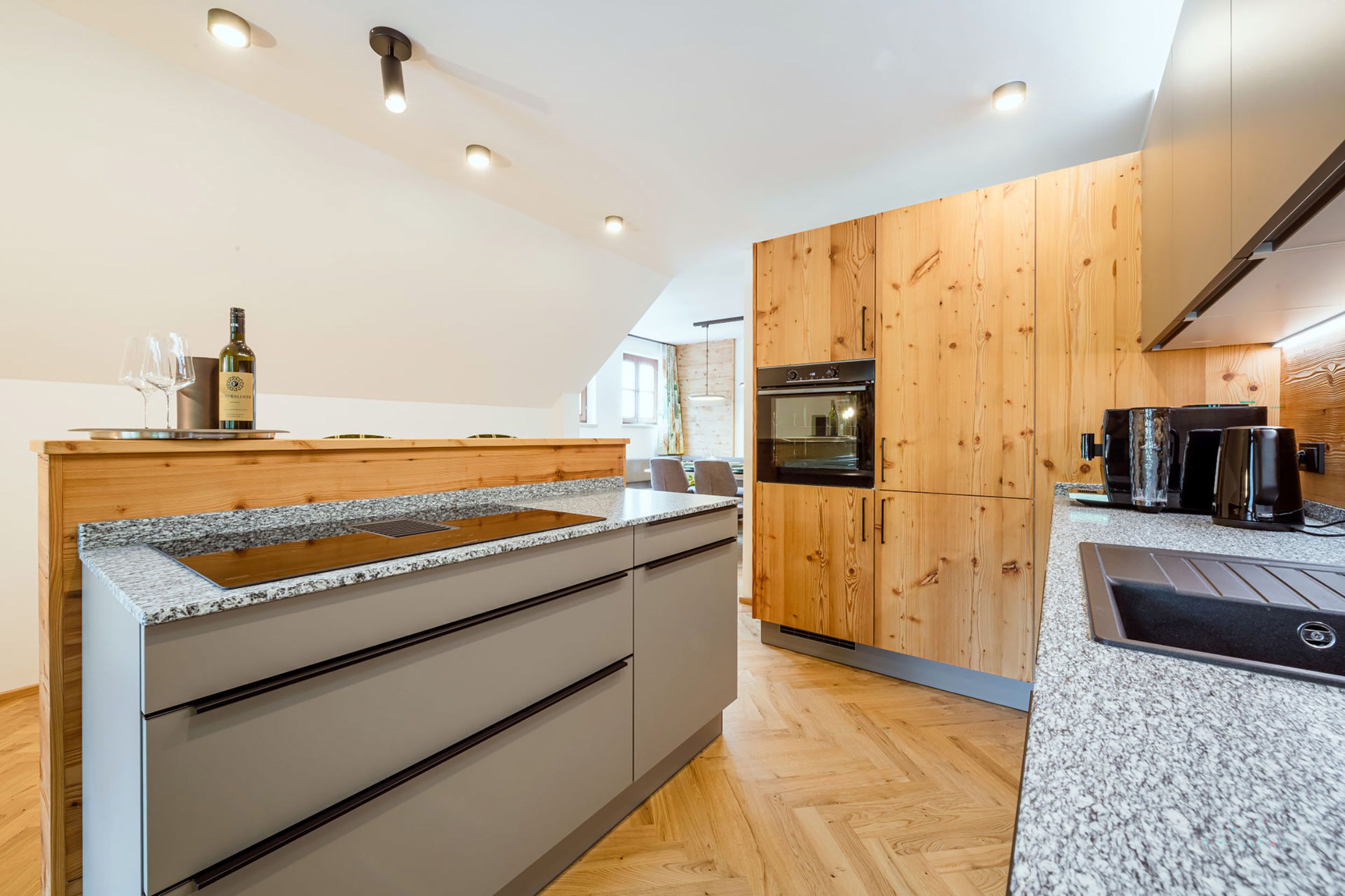 Una cucina moderna con mobili in legno, un piano di lavoro in granito ed elettrodomestici integrati.