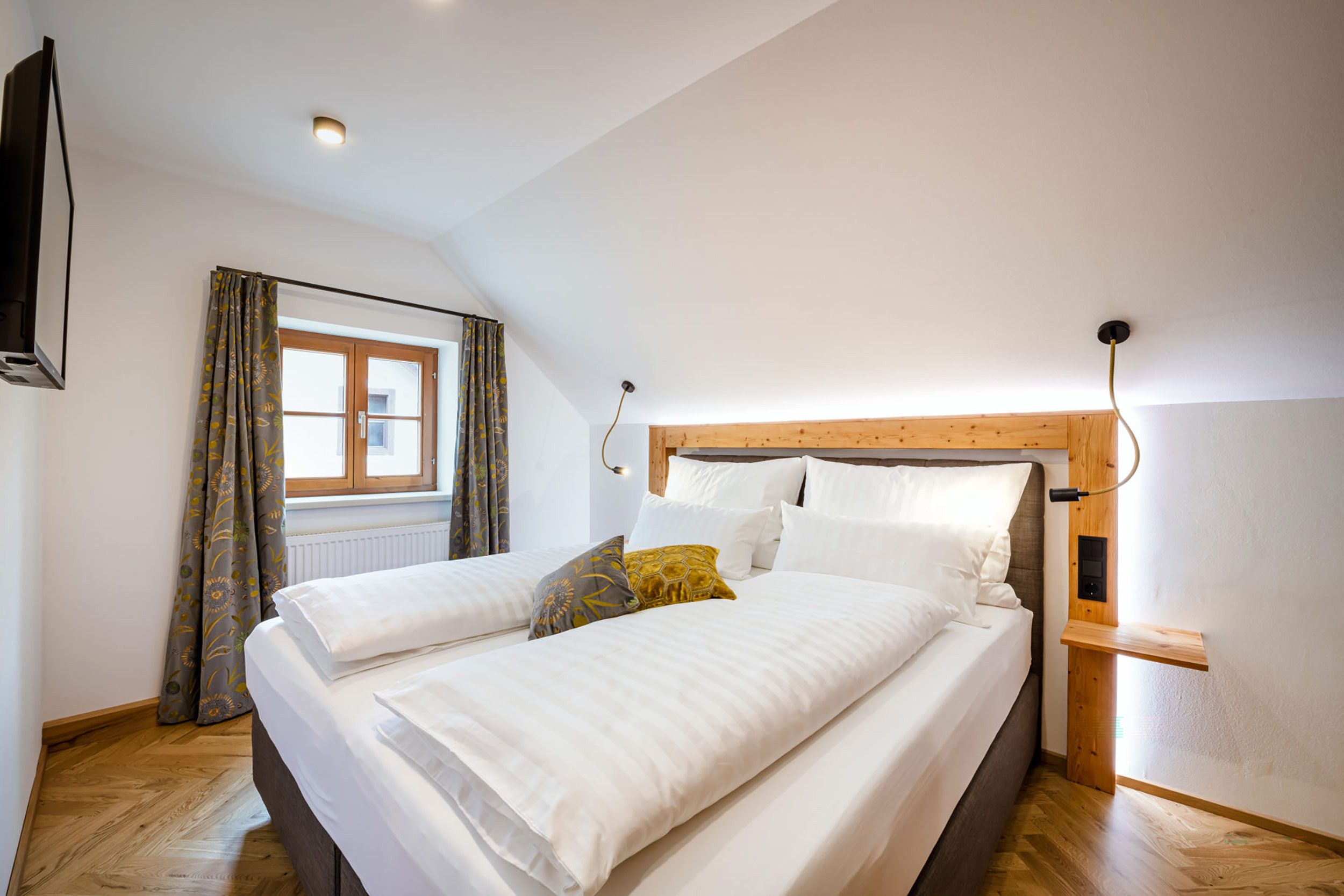 A bedroom with a bed, a window, and a wooden headboard.