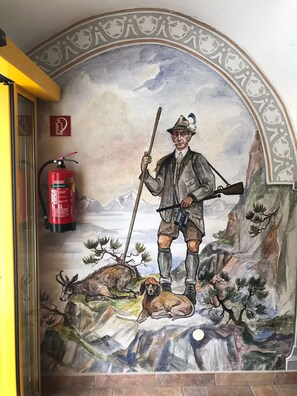 Un mural representa un home amb un fusell i un gos, un extintor i un paisatge de muntanya.