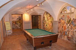 Una sala de billar amb una taula de bitlles, un mural i un senyal que indica el lavabo de homes.