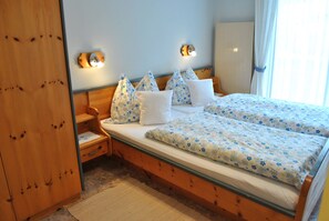 Un dormitorio con dos camas, un armario de madera, una mesita de noche y una lámpara de pared.