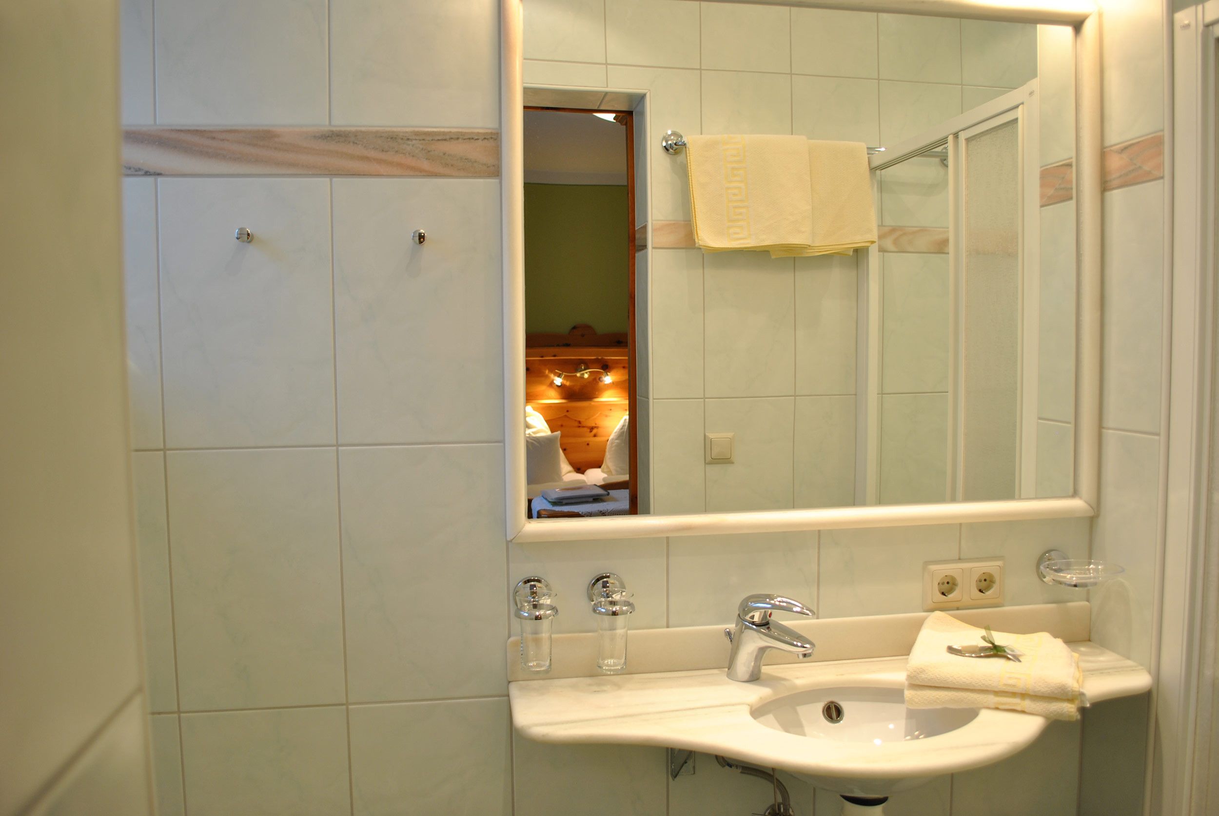 Ein Badezimmer mit einem weißen Waschbecken, einem Spiegel und einem Handtuchhalter.