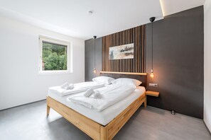 Une chambre moderne avec un lit en bois, une grande fenêtre et un tableau accroché au mur.