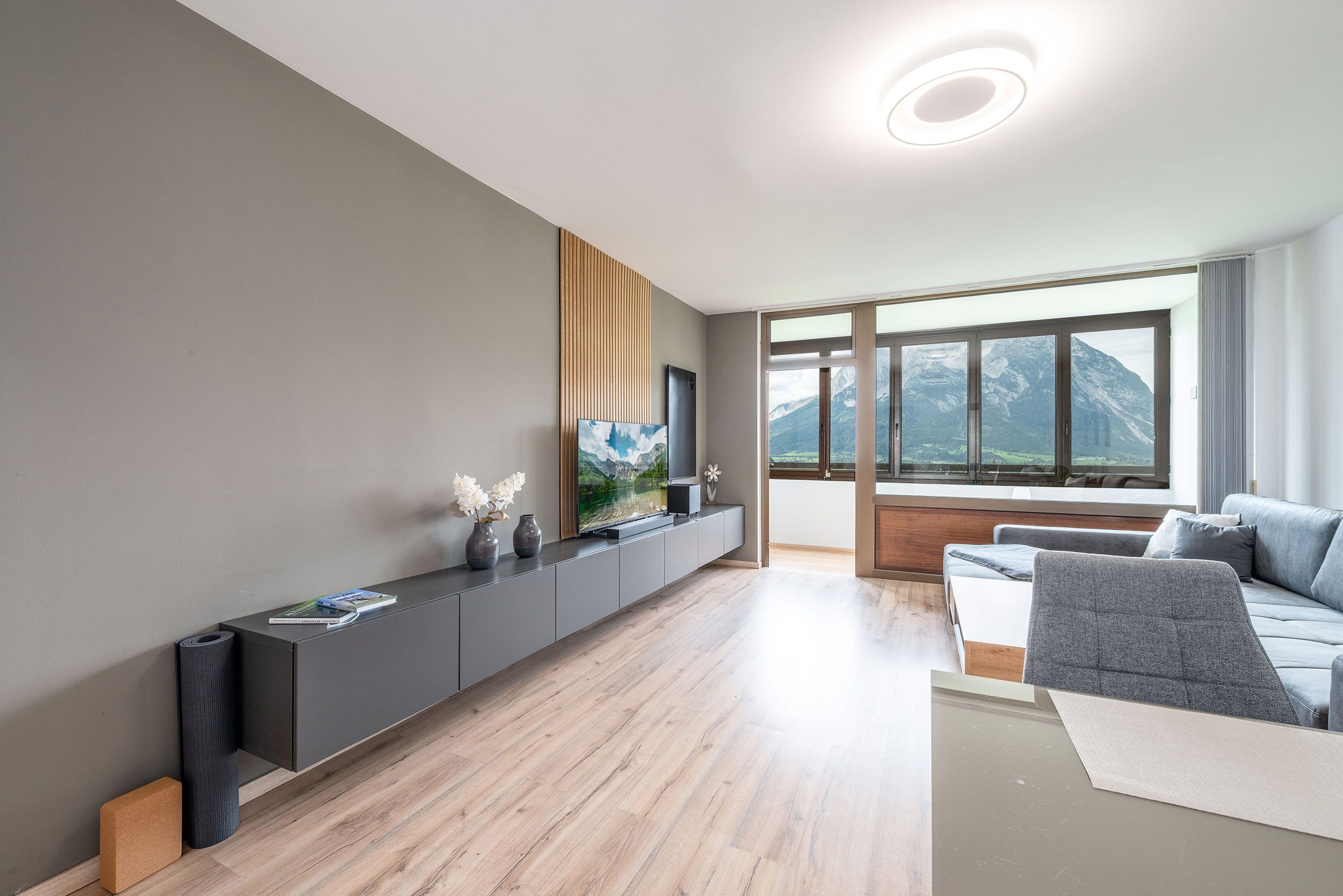Een moderne woonkamer met een flatscreen televisie, een houten console en een bank.