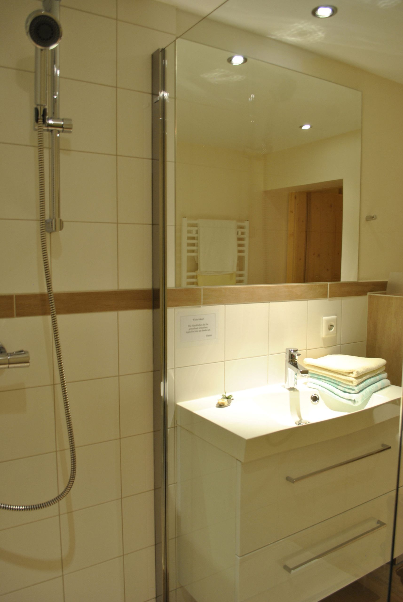 Ein Badezimmer mit Dusche, Waschbecken und Spiegel.