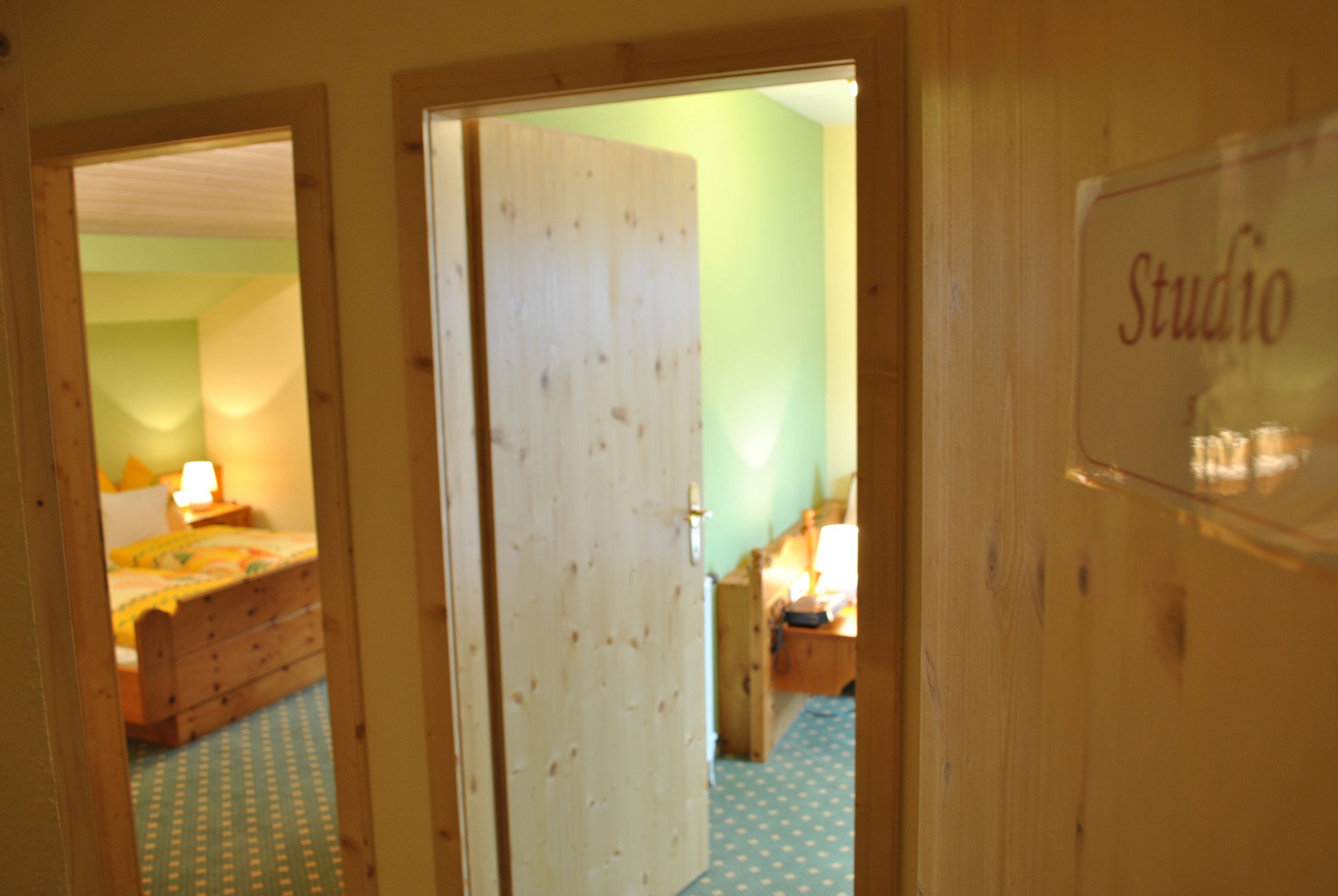 A wooden door with a sign reading 'Studio' and a glimpse of a room with a bed and a lamp.