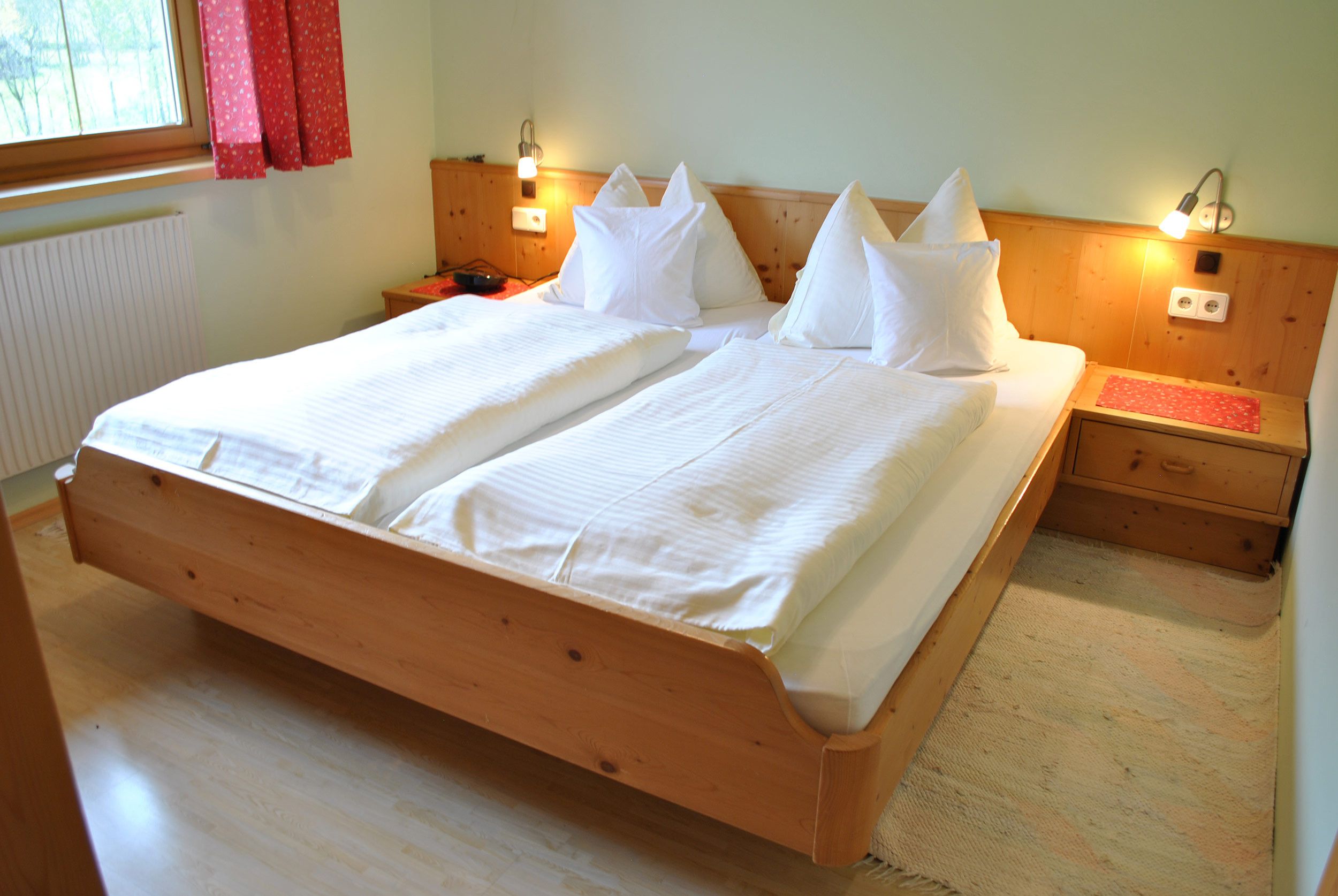 Una cama doble con estructura de madera, dos mesitas de noche y una mesita de noche con lámpara.