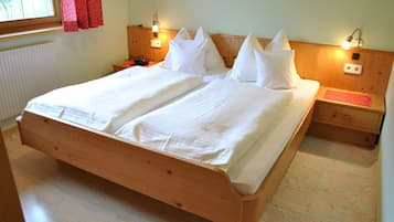 Una cama doble con estructura de madera, dos mesitas de noche y una mesita de noche con lámpara.