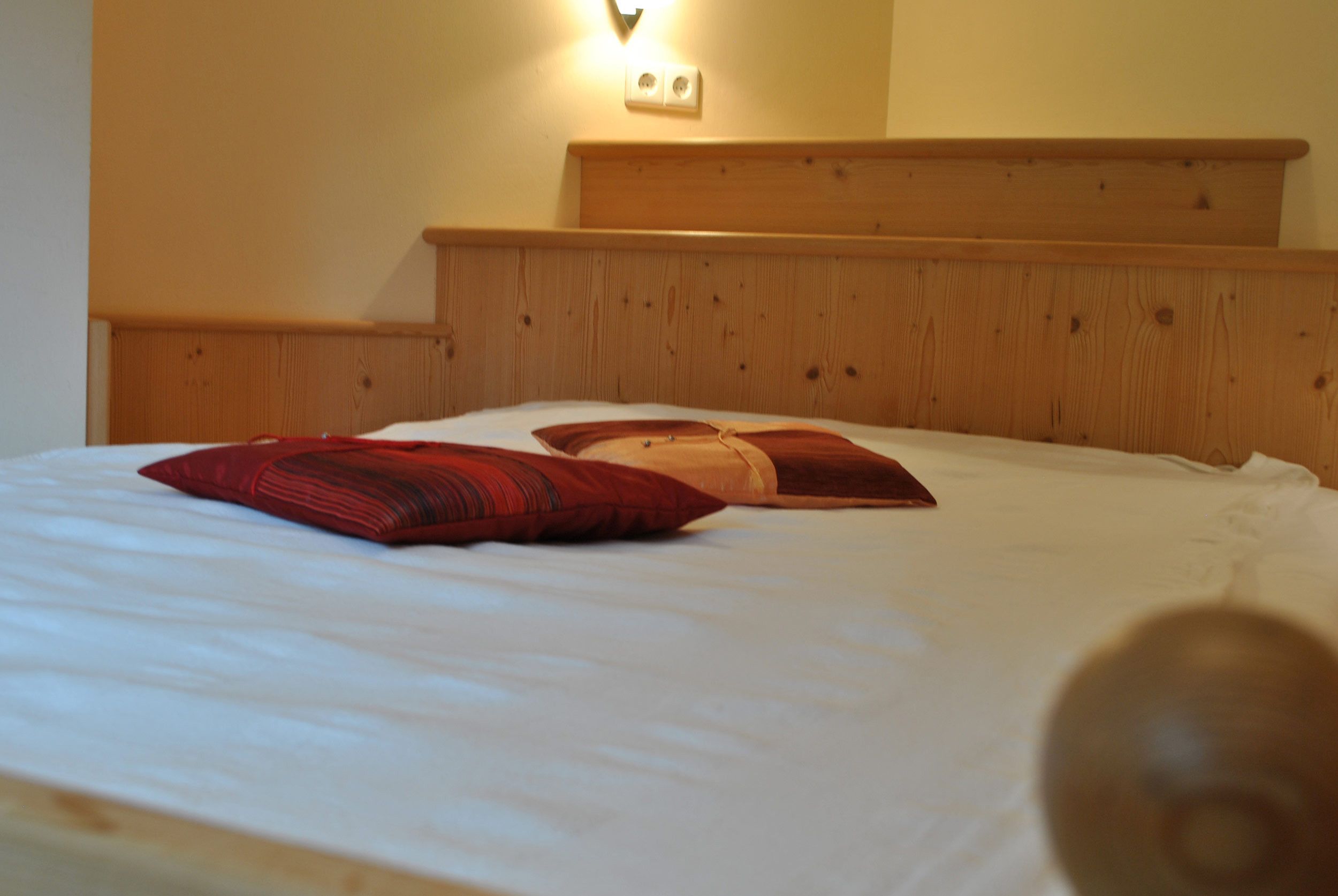 Un letto con un poggiatesta in legno e due cuscini.