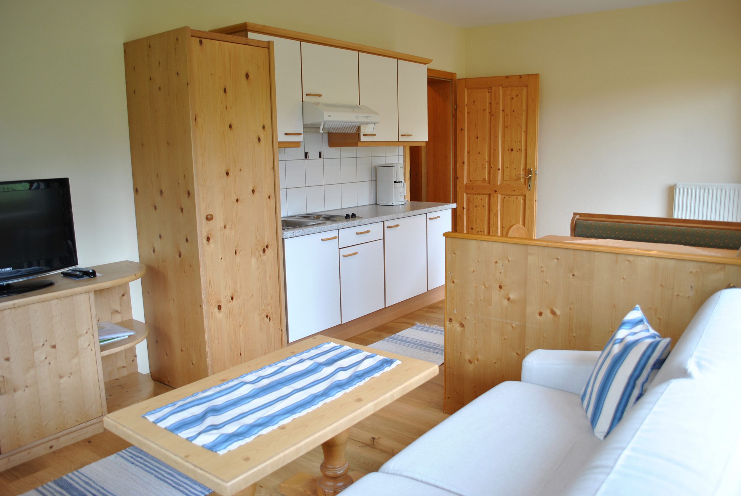 Een knus woongedeelte met een kitchenette, een bank en een televisie.