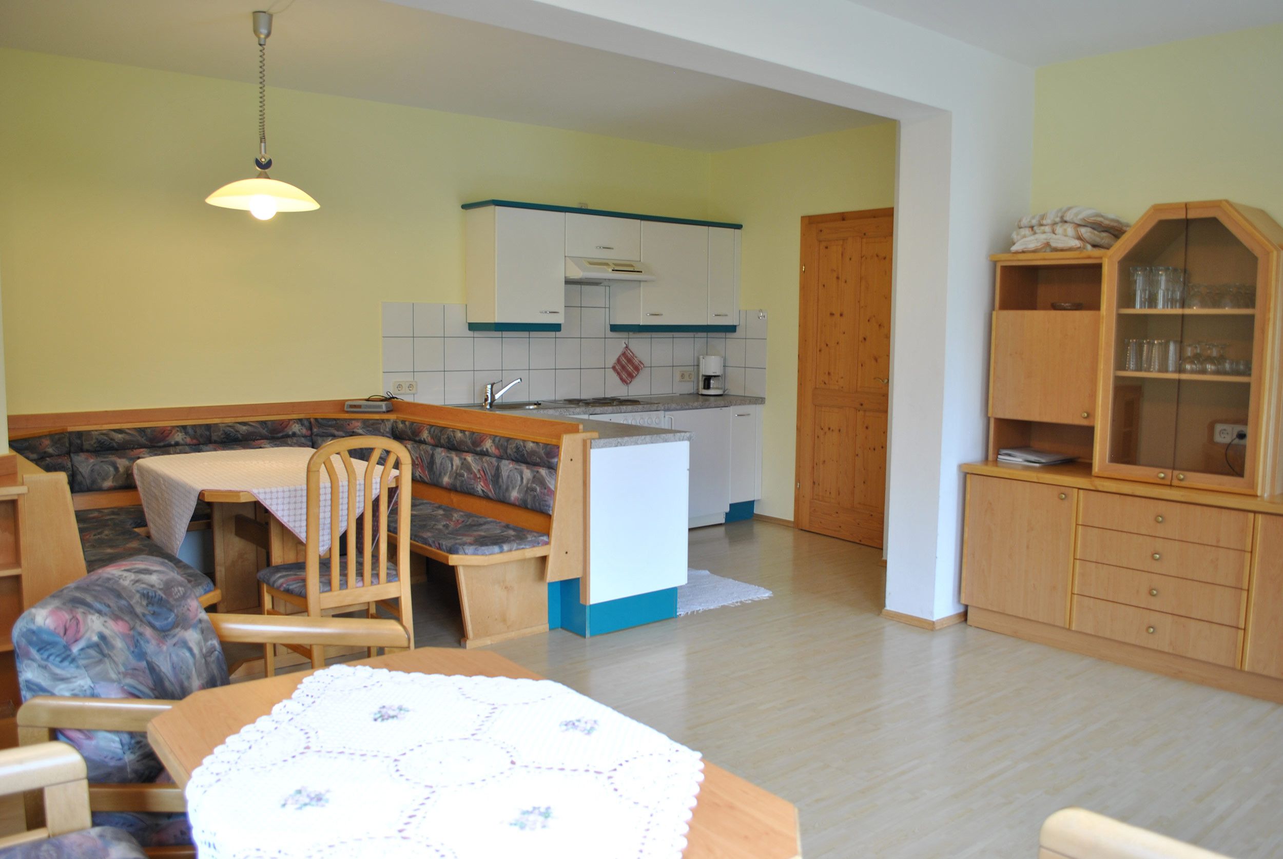 Un espacio habitable compacto con comedor, kitchenette y zona de estar con banco.