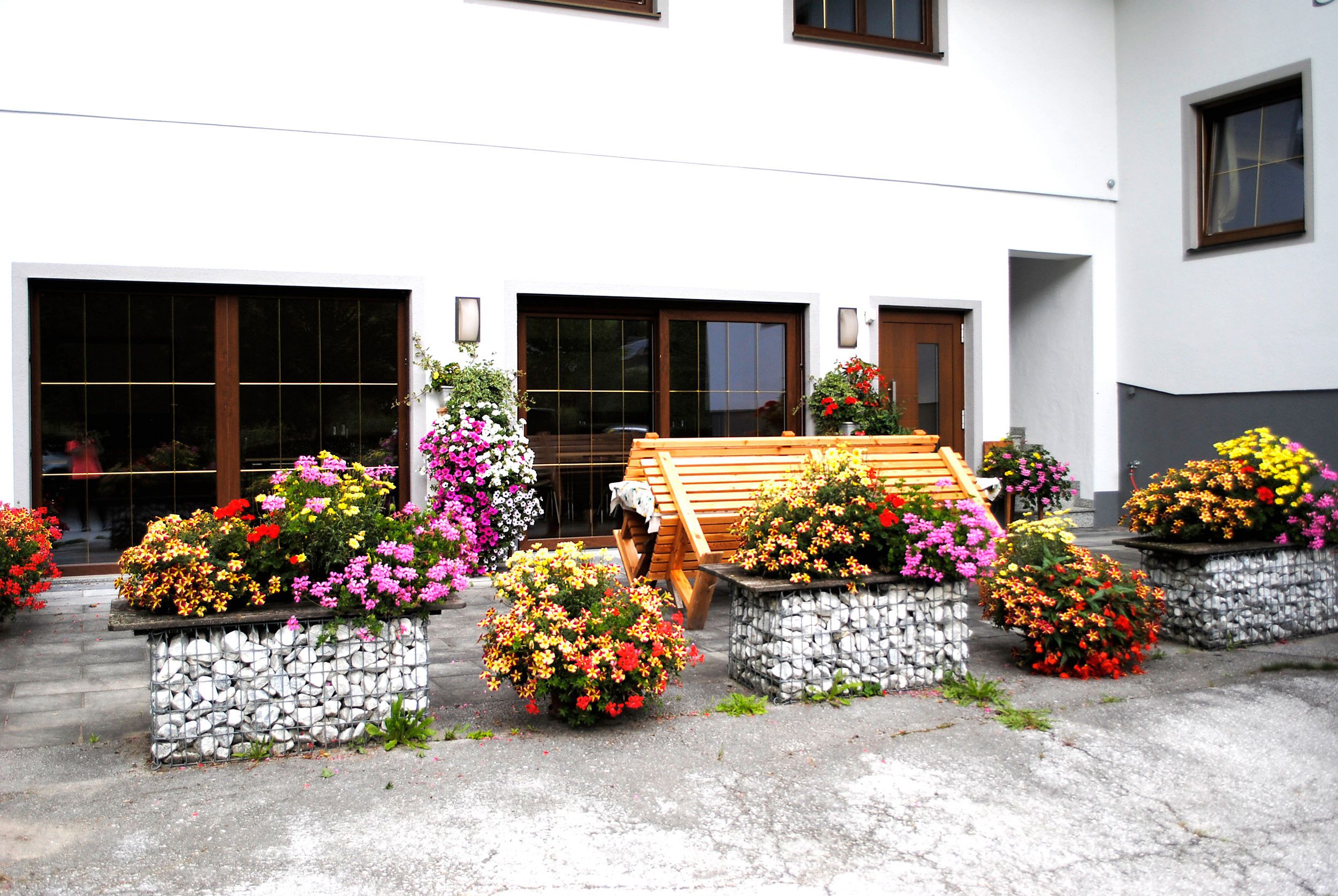A building with multiple garage doors, a wooden bench, and flower planters.