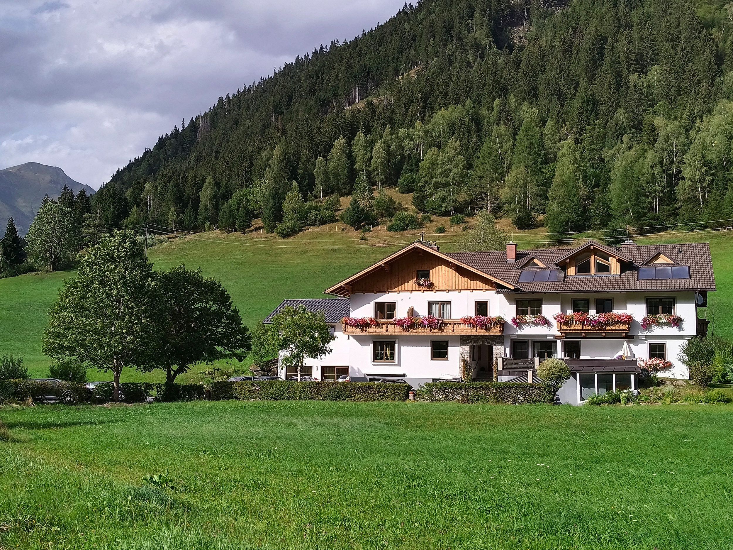 Una casa a due piani con tetto spiovente, facciata in legno e fioriere sui balconi.