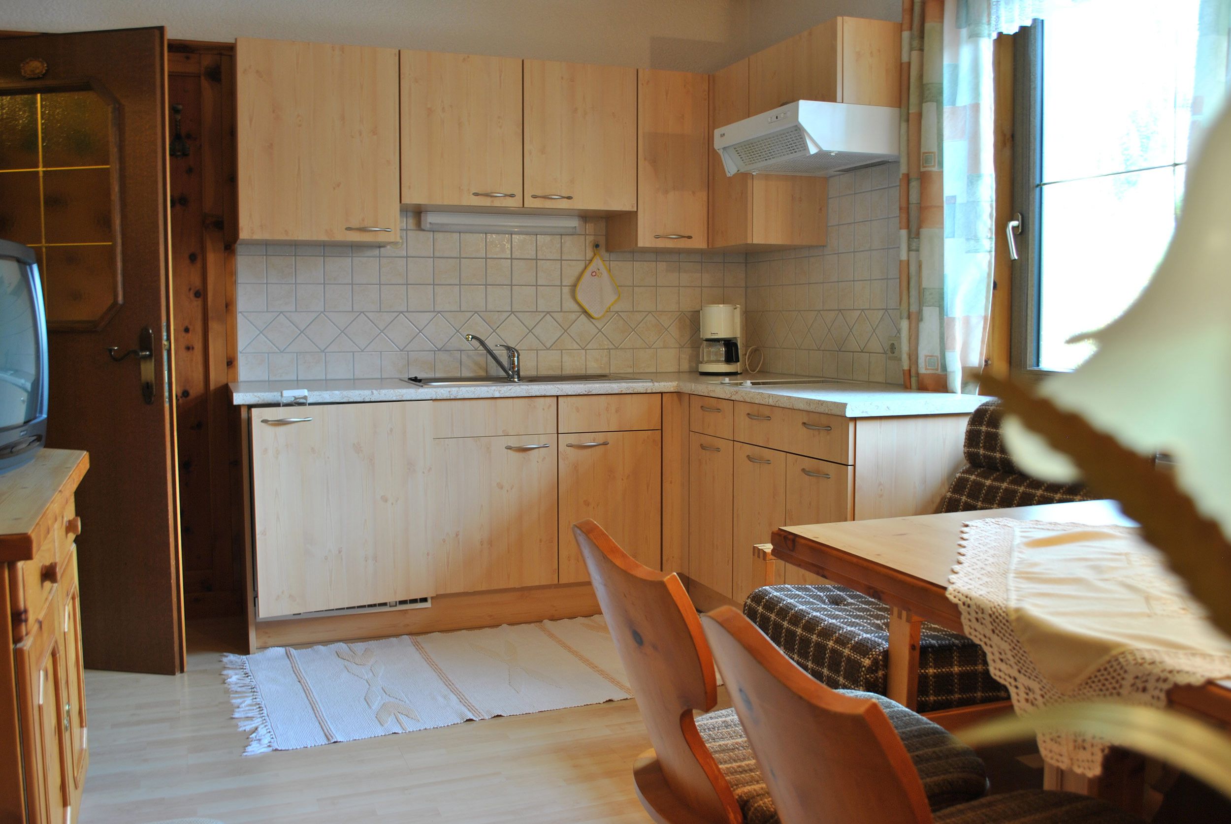 Een compacte keuken met houten kastjes, een ingebouwde magnetron en een koffiezetapparaat.