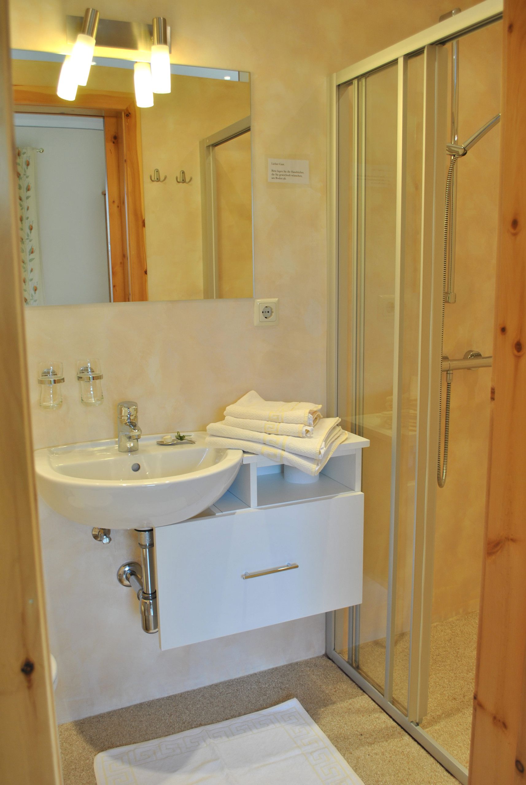 Un baño con lavamanos blanco, espejo y barra para toallas.