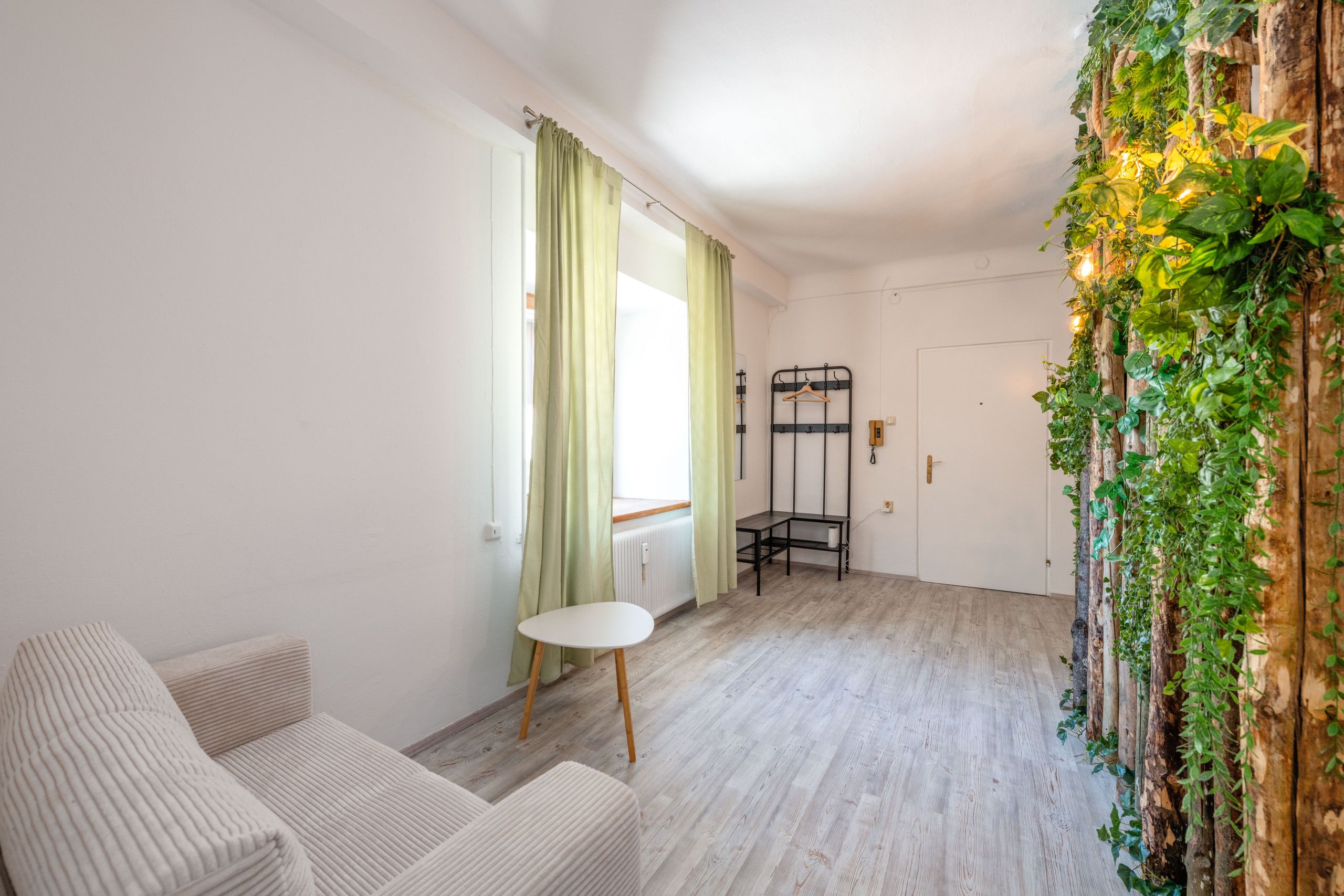 Una stanza con un letto, un tavolino, una sedia, un termosifone e una porta.
