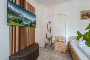 Camera da letto con un letto, un comodino, una sedia, una parete in listelli di legno, un quadro e una pianta.
