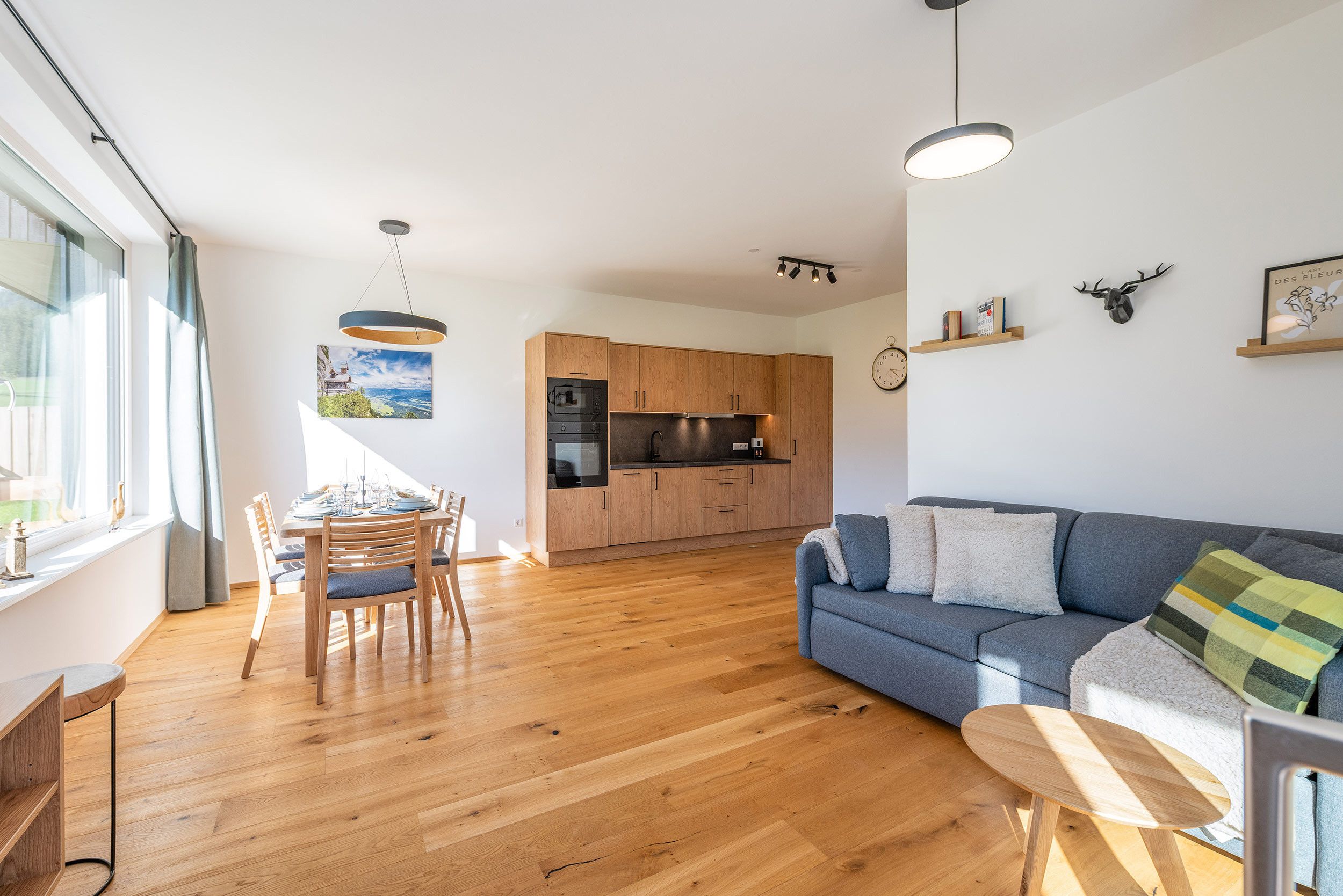 A modern kitchen with wooden cabinets, a dining area with a table and chairs, and a living room with a sofa and a coffee table.