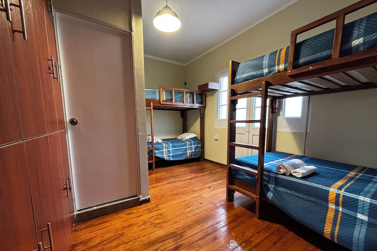 A dormitory room with bunk beds, a wardrobe, and a wooden floor.