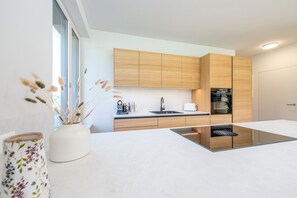 Een moderne keuken met houten kastjes, een zwart inductiekookveld en een wit aanrecht.
