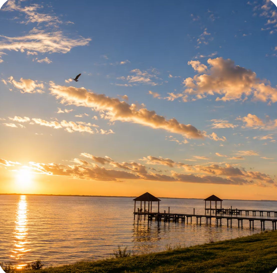 A sunset over a calm body of water with two wooden gazebos on piers.