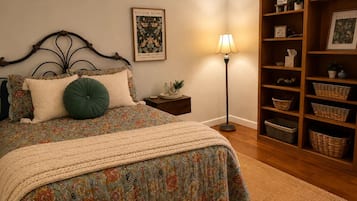 A bedroom with a bed, a nightstand, a lamp, a bookshelf, and a framed picture on the wall.
