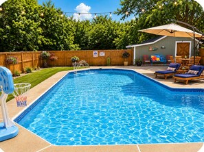 En swimmingpool med en basketballkurv, omgivet af et træhegn, og en terrasse med udendørs møbler.