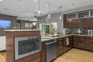 Une cuisine moderne dotée d’un four encastré, d’un lave-vaisselle et d’un grand îlot central avec un évier.