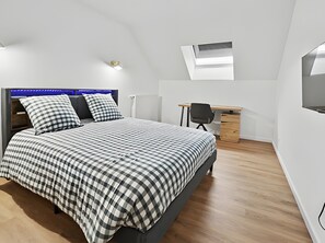 A bedroom with a bed, desk, and an air conditioning unit. - Holiday Home 'Player One Comfortable House' with Private Terrace, Private Garden and Wi-Fi (Villiers-le-Sec)