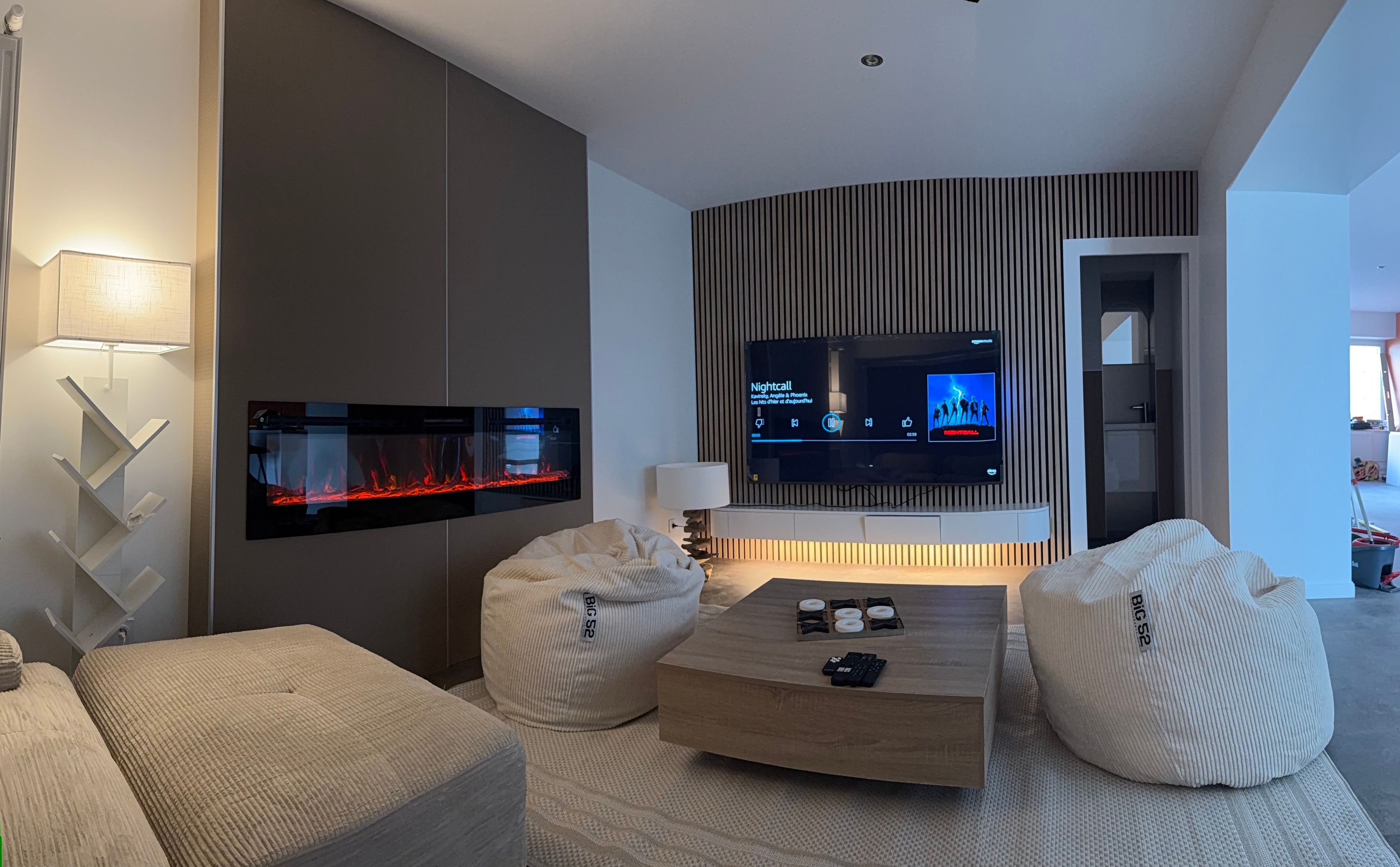 A modern living room with a flat-screen TV, a fireplace, and comfortable seating.