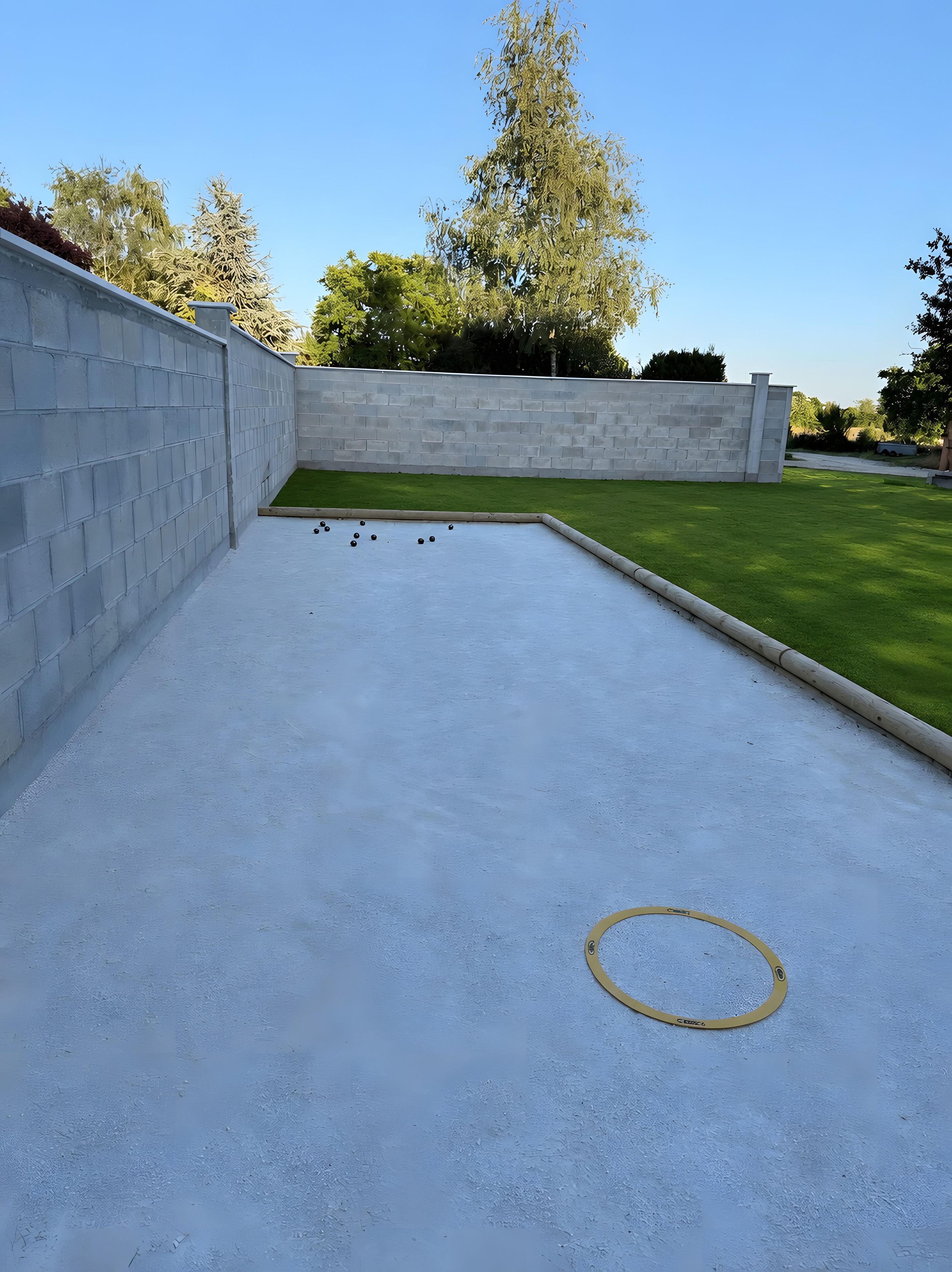 A courtyard with a white brick wall, a green lawn, and a billiards table.