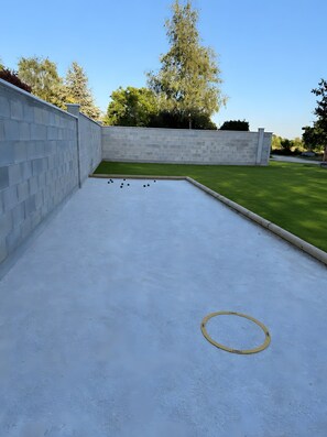 A courtyard with a white brick wall, a green lawn, and a billiards table. - Holiday Home 'Player One Comfortable House' with Private Terrace, Private Garden and Wi-Fi (Villiers-le-Sec)