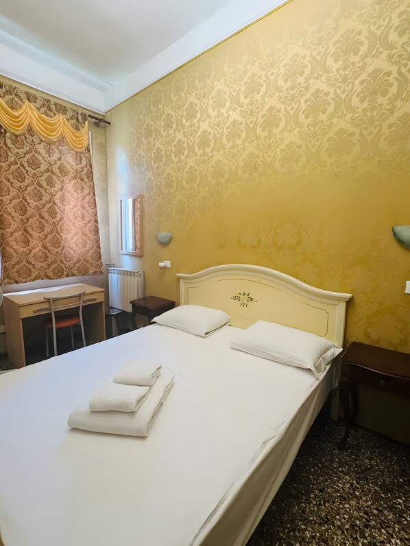 Ein Hotelzimmer mit Bett, Schreibtisch, Stuhl und Heizkörper.