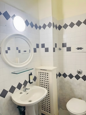 Ein Badezimmer mit einem weißen Waschbecken, Spiegel und WC.
