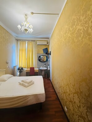Ein Hotelzimmer mit Bett, Schreibtisch mit Stuhl, Waschbecken und Spiegel.