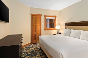 A hotel room with a bed, bedside table, lamp, TV, wardrobe, and a window. - Chelan | Family Lake Retreat | Pool + Lake | 3BR Sleeps 8 (Chelan)