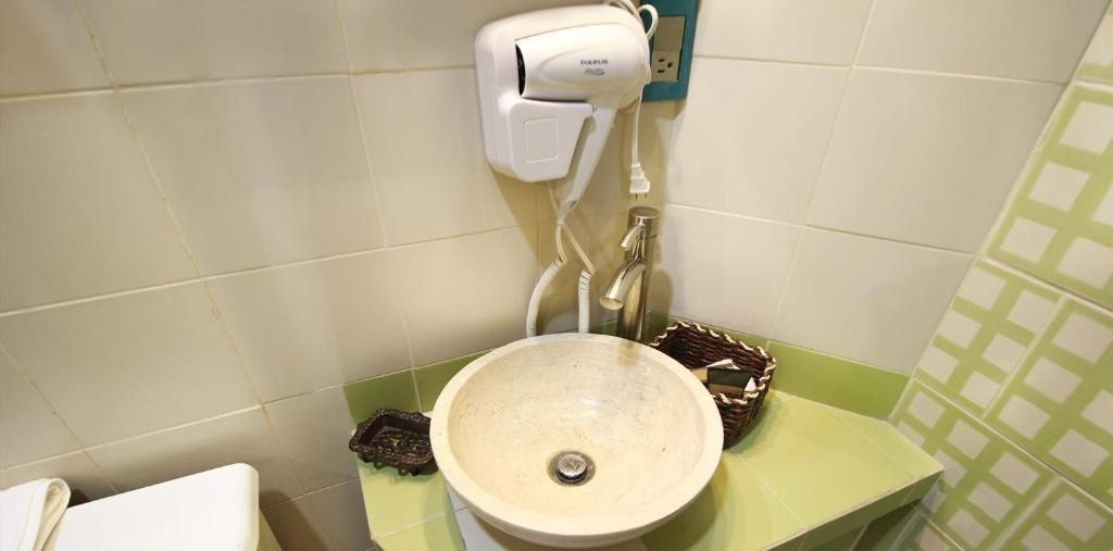 Une salle de bain équipée d’un lavabo, d’un sèche-cheveux et d’un plan de toilette vert.