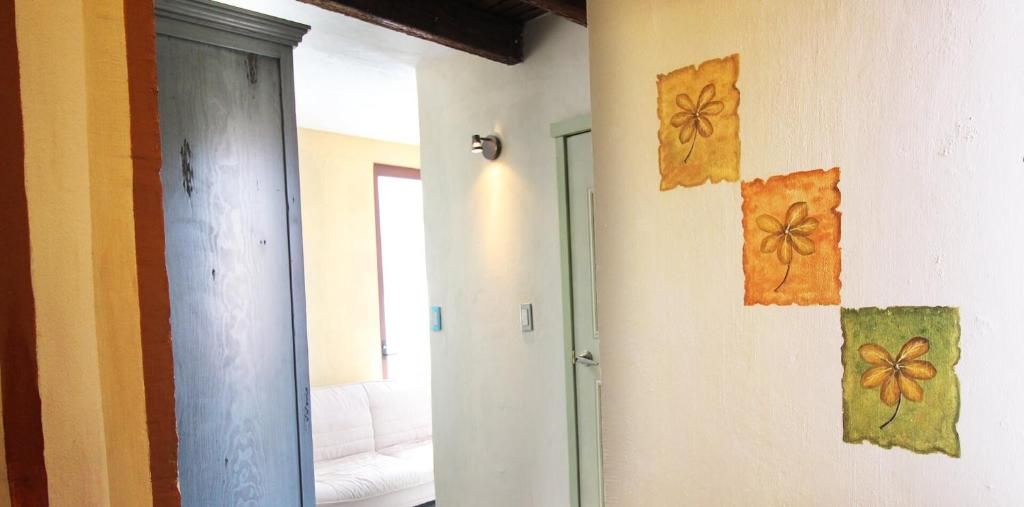 A hallway with a door, a light switch, and a wall with three flower paintings.
