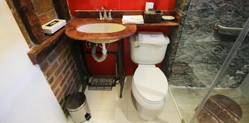 A compact bathroom with a sink, toilet, and shower.