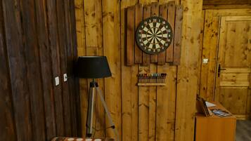 Een kamer met een dartbord, een tafel met een geruit patroon en een lamp.