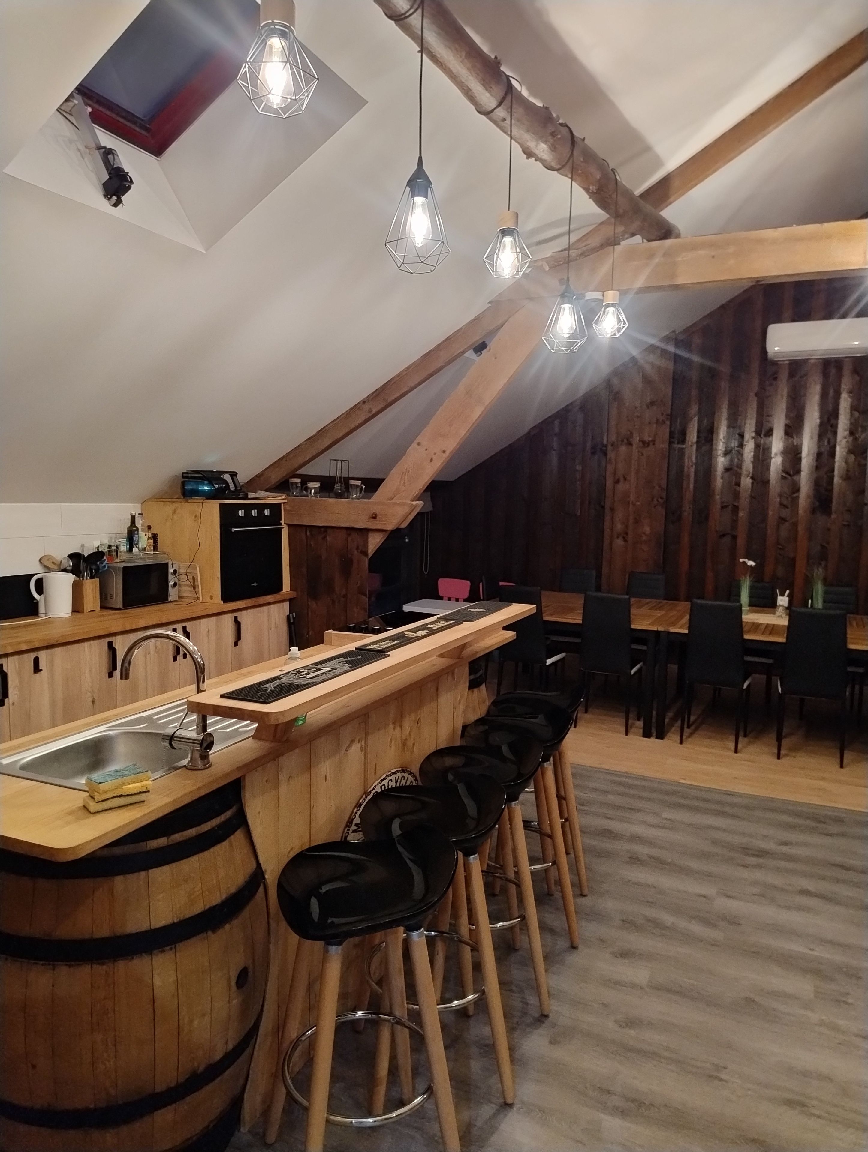 A kitchen with a wooden bar, stools, and hanging pendant lights.